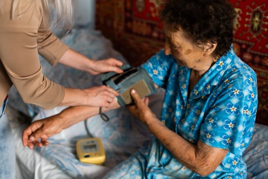 Female doctor measuring blood pressure of senior woman photo