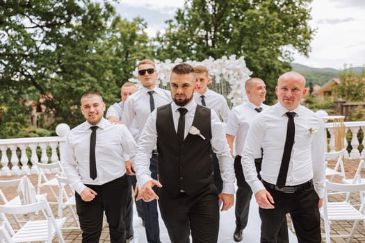 Cheerful, young, energetic witnesses of the groom next to the groom. Friends congratulate the groom. The groom in a vest and his friends in white shirts pose near the wedding arch. Wedding in nature. photo