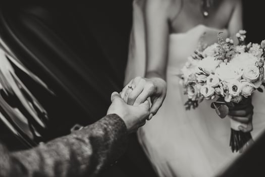 Groom helps happy young bride to get out of wedding car. black and white photo