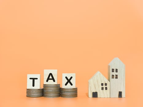 Miniature house, Wooden blocks with the word TAX and stack of coins. The concept of payment tax for house, Property investment, House mortgage, Real estate. photo