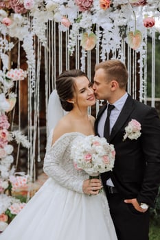 The groom kisses his bride on the temple against the background of beautiful nature on a summer day. Art. Selective focus. photo