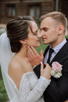 The groom kisses his bride on the temple against the background of beautiful nature on a summer day. Art. Selective focus. photo