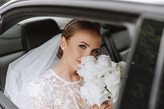 The bride looks out of the car window. Close-up portrait of a pretty shy bride in a car window. Bride smile emotions photo