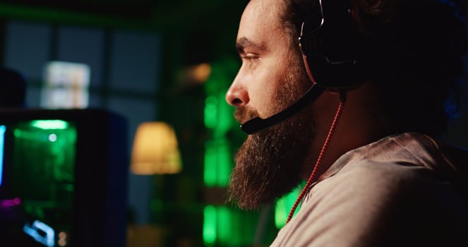 Man playing FPS videogame with friends, talking through headphones mic, close up shot. Gamer competing in PvP online multiplayer game with teammates, shooting enemies with futuristic gun photo
