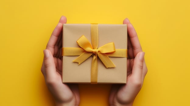 AI generated A Yellow Background Showcasing a Gift Box Held by Human Hands in Close-up View photo