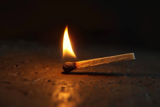 AI generated Lighted matchstick rests on a textured brown wooden surface photo