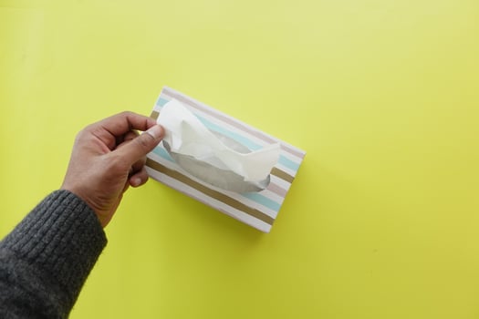 hand pull out a piece of tissue from tissue paper box photo