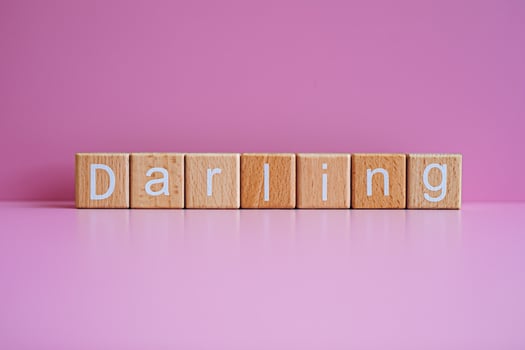 Wooden blocks form the text Darling against a pink background. photo