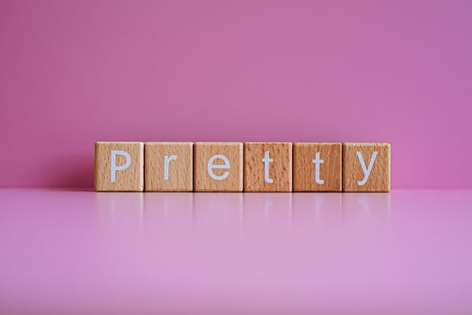 Wooden blocks form the text Pretty against a pink background. photo