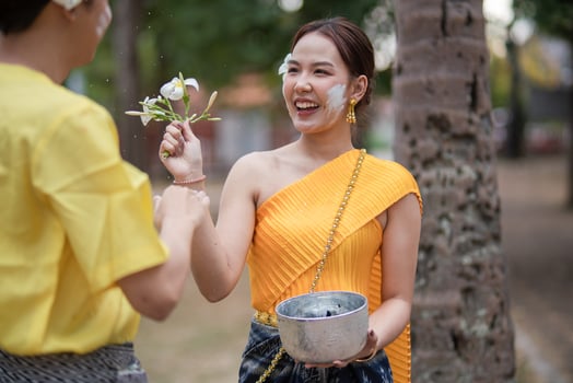 A beautiful Young Thai couple wearing Thai costumes playing in the water during Songkran in the temple photo