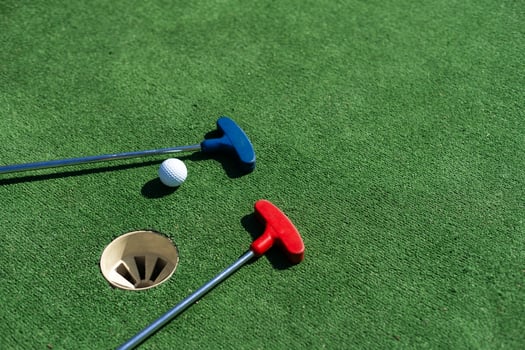 colorful golf putters with golf balls on synthetic grass photo