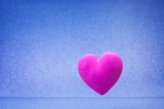 Plain blue background with little violet red heart photo