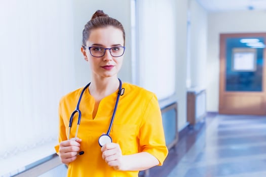 Doctor beautiful girl smiling. portrait in yellow uniform with a stethoscope to the corridor of the hospital. Health care. background photo
