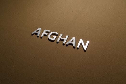 the word afghan laid with silver metal letters on rough tan khaki canvas fabric photo