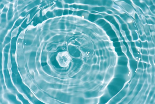 Water surface. Bluewater waves on the surface ripples blurred. Defocus blurred transparent blue colored clear calm water surface texture with splash and bubbles. Water waves with shining pattern. photo