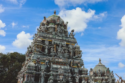 A tall tower featuring intricately carved statues at an Indian temple. photo