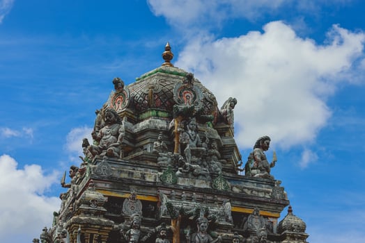 A tall tower featuring intricately carved statues at an Indian temple. photo