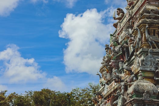 A tall tower featuring intricately carved statues at an Indian temple. photo
