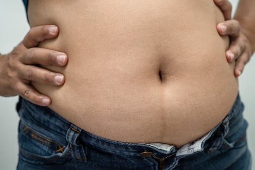 Overweight Asian woman show and use hand to squeeze fat belly. photo