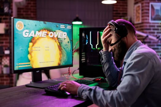 Gamer feeling depressed after losing online multiplayer action videogame match, being outsmarted by rival players. Dejected man getting headache from frustration after seeing game over screen photo