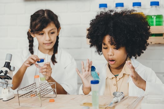 Young children playing exciting with chemistry science kits in school classroom with friend class mate photo