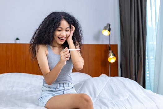 Young African mix race woman is in happiness after doing pregnancy test using HCG for motherhood, fertilization and maternity usage photo