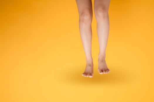 Indulge in the luxurious sensation of velvety foot touch with a 30s person's elegant close up on vibrant yellow backdrop. photo