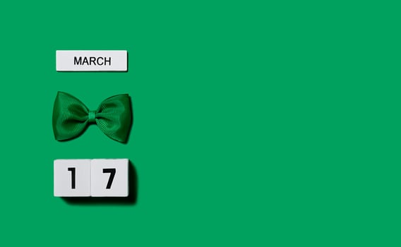 St. Patrick's Day background. Wooden calendar with a leprechaun bow on a green background. Banner. Copy space. photo
