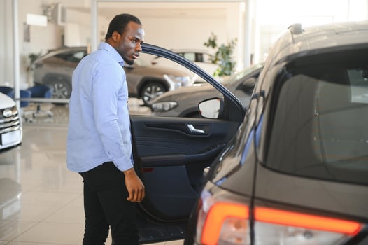 Handsome African man choosing a new car at the dealership photo