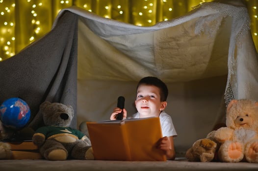 boy reading book with flashlight in tent at night. photo