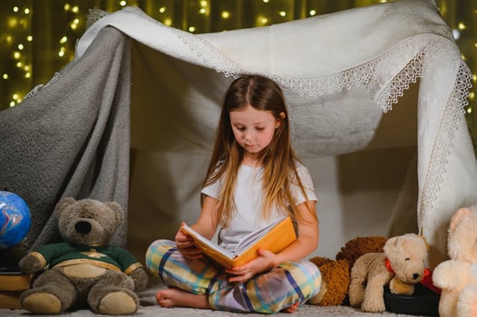 Reading and family games in children's tent. Little girl with books and flashlight before going to bed photo