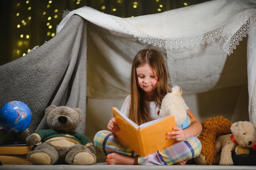 A pretty little girl reading a book on the floor under the lamp. Children and education photo