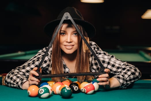 A girl in a hat in a billiard club with balls in her hands.Playing billiards photo