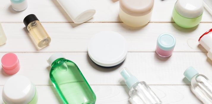 Close-up view of cosmetic bottles, jars, containers and sprays on white wooden background. Beauty concept with copy space photo