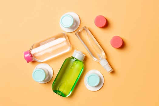 Top view composition of small travelling bottles and jars for cosmetic products on colored background. Facial skin care concept with copy space for your design photo