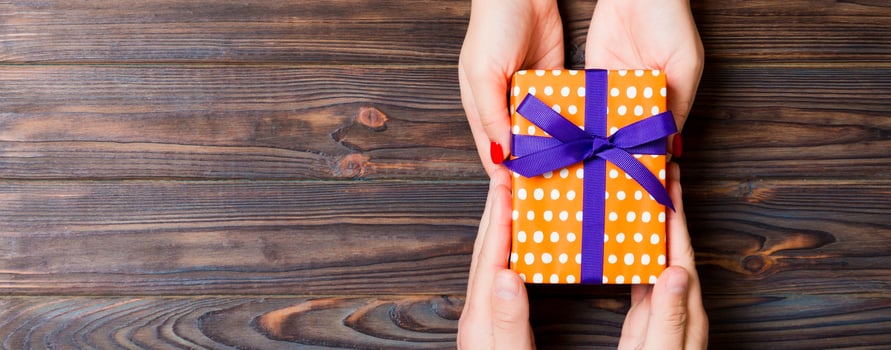 Top view of giving and receiving a gift on wooden background. Present in male and female hands. Love concept. Copy space photo