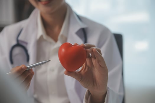 Hands of doctor woman holding red heart, showing symbol of love, human support to patient, promoting medical insurance, early checkup for healthcare, cardiologist help. Close up of object photo