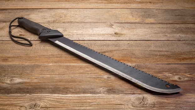 bush clearing machete with carbon steel blade and saw against rustic wooden deck photo