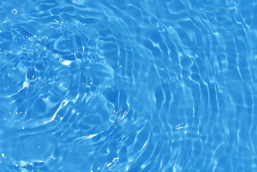 Bluewater waves on the surface ripples blurred. Defocus blurred transparent blue colored clear calm water surface texture with splash and bubbles. Water waves with shining pattern texture background. photo