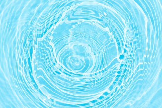 Bluewater waves on the surface ripples blurred. Defocus blurred transparent blue colored clear calm water surface texture with splash and bubbles. Water waves with shining pattern texture background. photo