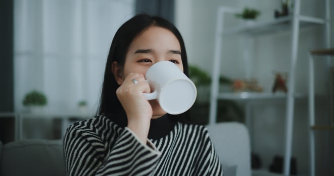 Portrait of Relaxing young woman holding cup enjoy smell coffee or tea and drinking with happiness in morning while sit on sofa in living room,Free time,take break in home,smiling photo