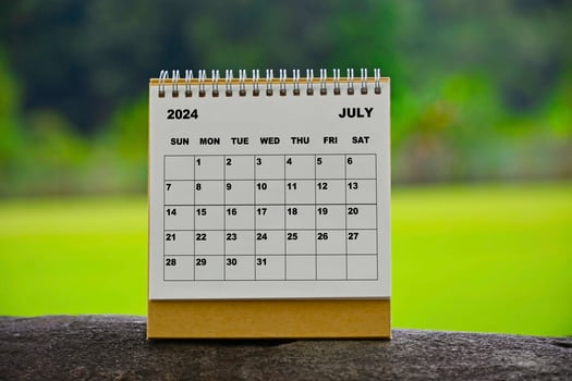 July 2024 white calendar with green blurred background. photo