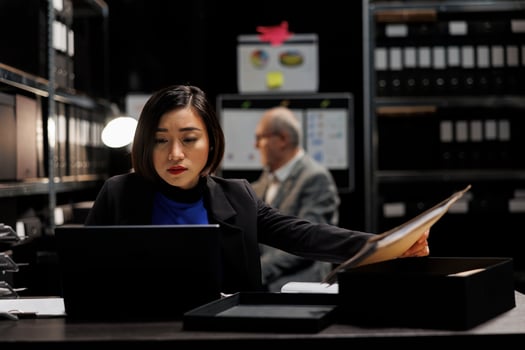 Asian private investigator starting criminal investigation case, comparing criminal investigation details. Detective woman in archive file cabinet office filled with criminology folders photo