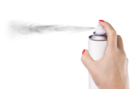 Woman spraying paint from can on white background photo