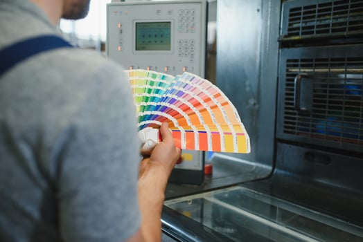 Man working in printing house with paper and paints photo