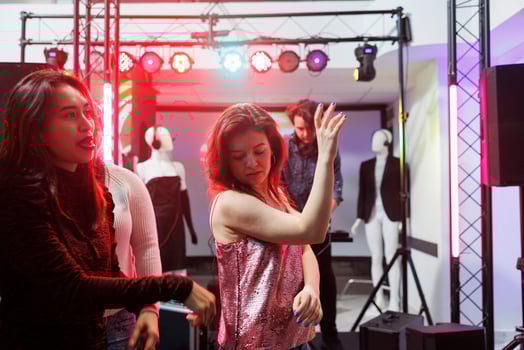 Women dancing and partying at social gathering in nightclub illuminated with stage spotlights. Girl clubbing and having fun on dancefloor, enjoying nightlife leisure activity photo