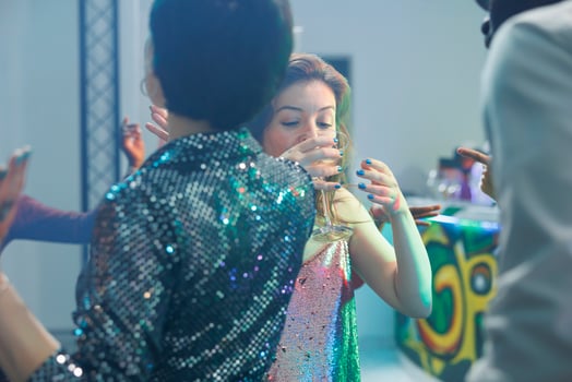 Women drinking alcohol beverages while dancing and partying in nightclub. Young girl clubbers holding glass and enjoying social gathering event with friends on club dancefloor photo