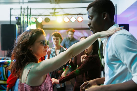 Young couple in love dancing while partying and relaxing in nightclub. Caucasian girlfriend and african american boyfriend making passionate moves on dancefloor while clubbing photo