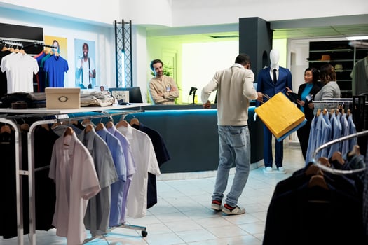 Clothing store excited client dancing with bags after buying trendy apparel with discount. Happy satisfied african american man holding purchase packages and enjoying shopping in boutique photo
