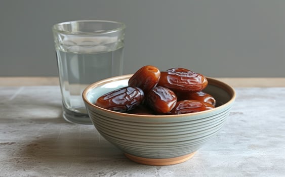 AI generated A bowl of dates next to a glass of water, islamic traditional clothing picture photo